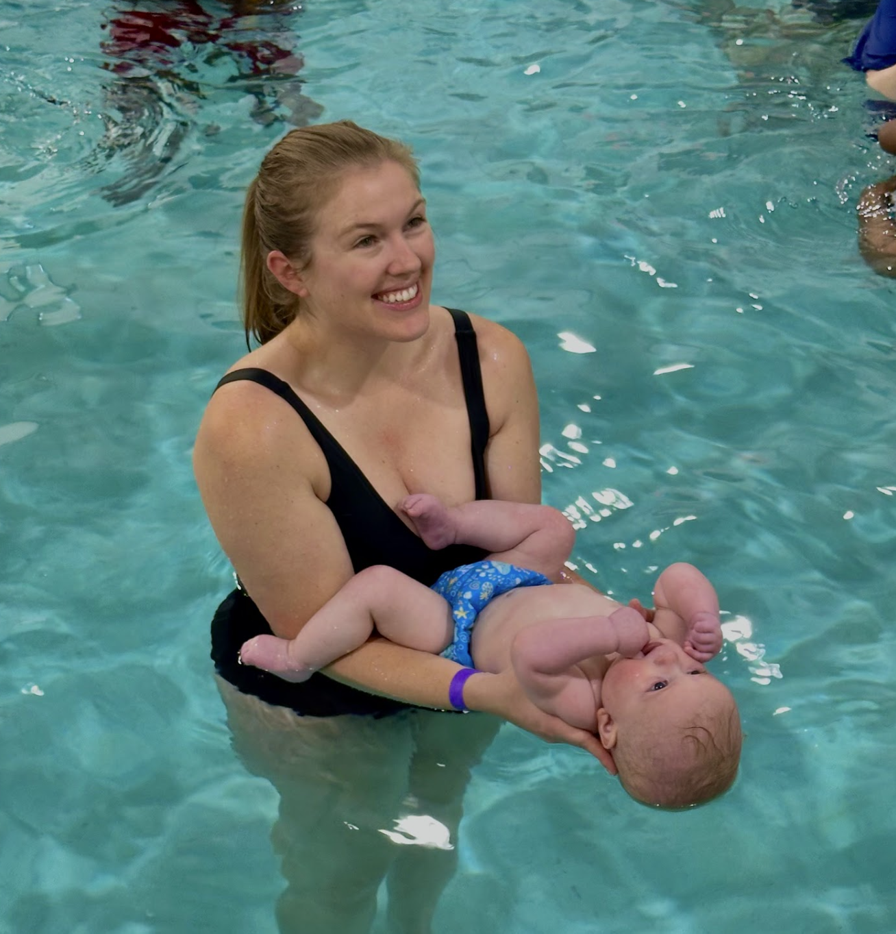 A baby taking swim lessons.