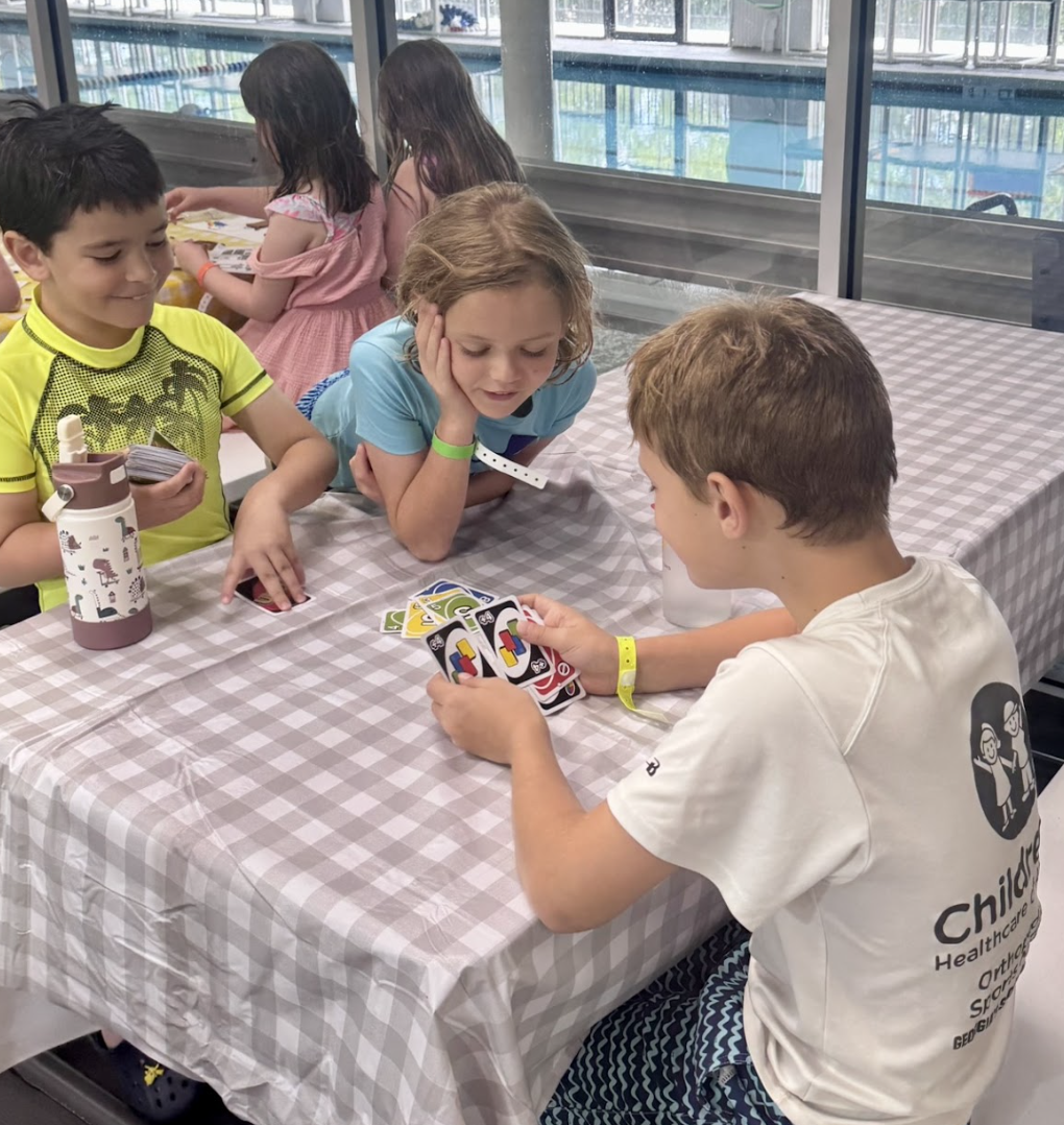 3 kids holding up artwork they made during Camp H2O