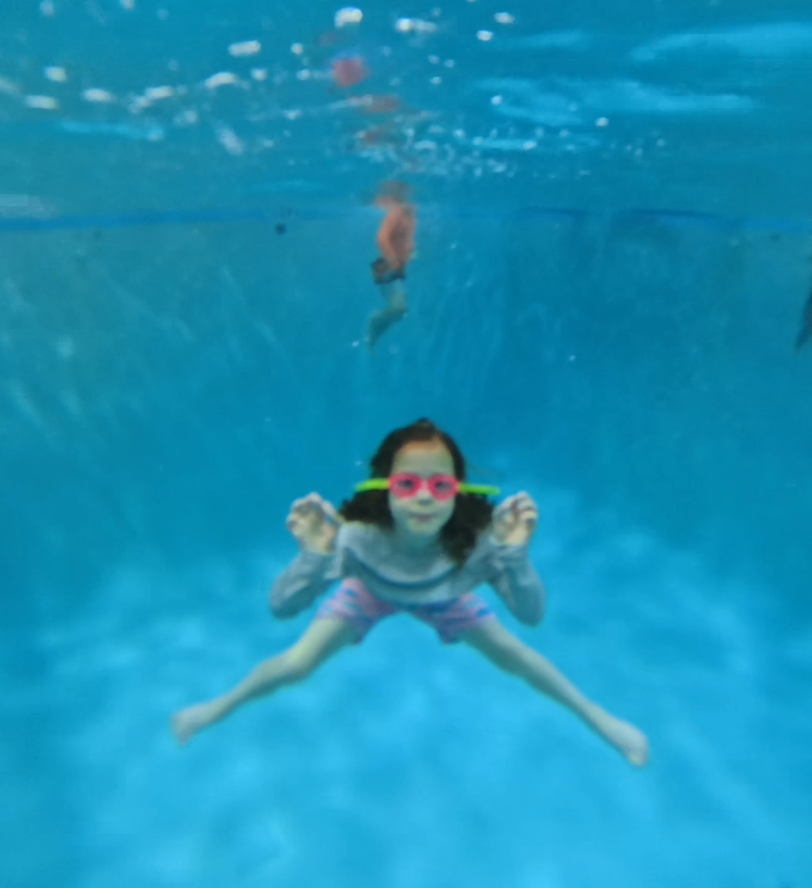 A kids jumping in a pool with children in it.